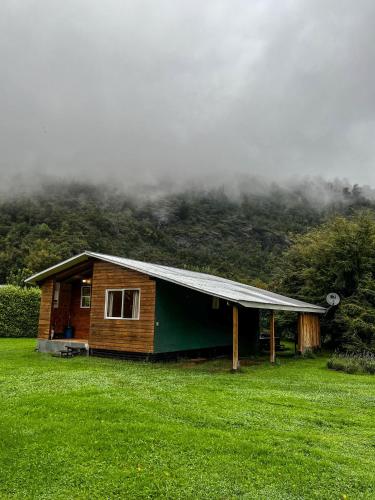 a small cabin in a field with a mountain at Cabañas Tranquihue Llifen in llifen