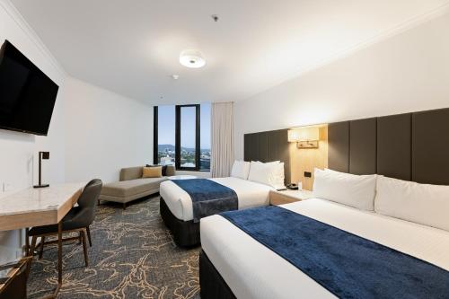 a hotel room with two beds and a flat screen tv at Hotel Grand Chancellor Brisbane in Brisbane