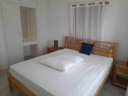 a bed with white sheets and a blue pillow at Dan Beach Apartment in Trou dʼ Eau Douce