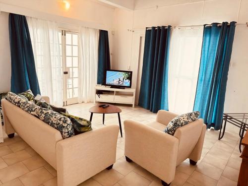 a living room with two couches and a tv at Dan Beach Apartment in Trou dʼ Eau Douce