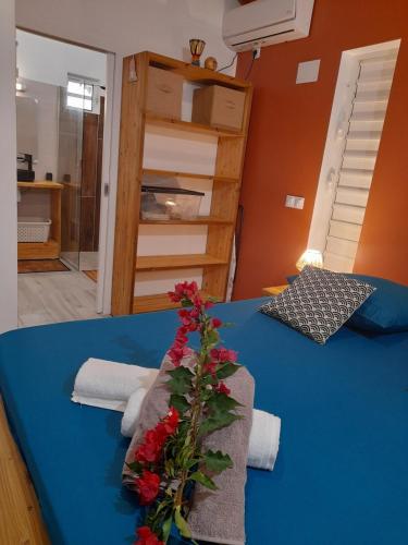 a blue bed with a bouquet of flowers on it at Bwa Ka - Havre de paix et cosy in Saint-François