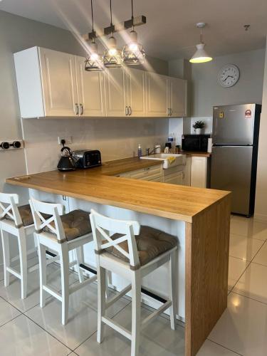 a kitchen with a wooden counter with chairs and a refrigerator at Mus Lim Mimi Homestay Gamuda Gardens in Rawang