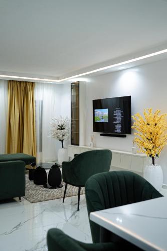 sala de estar con sillas verdes y TV de pantalla plana en Nest Luxury Apartment, en Ilorin