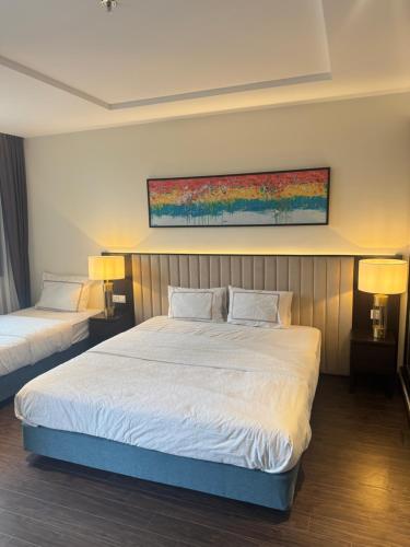 a bedroom with two beds and a painting on the wall at Khánh Phong Apartment Premire Sapphire Hòn Gai Hạ Long in Ha Long