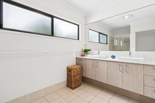 Un baño con dos lavabos y un espejo. en Currimundi Lake House, en Kawana Waters