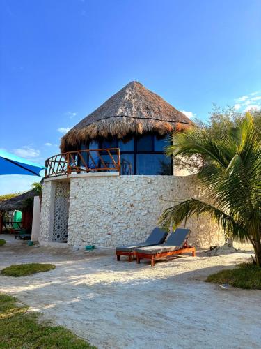 a building with two lounge chairs in front of it at Cabanas Jaalkab in Chelem