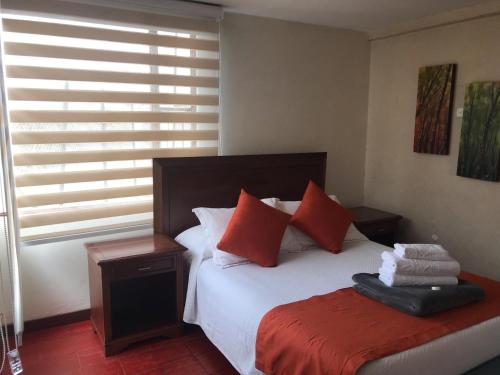 a bedroom with a bed with red pillows at hotel el portal de las Flores, Alojamiento Rural in Chía