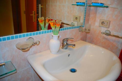 a bathroom sink with a vase with flowers in it at Turas Club Case Vacanze in Bosa