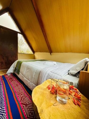 a room with a bed and a table with a glass at Salkantay Glamp in Colcapampa
