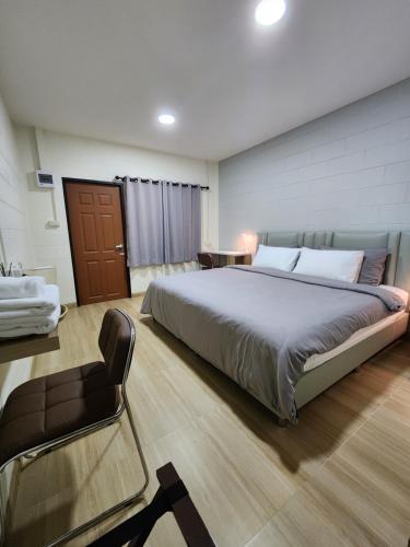 a bedroom with a large bed and a chair at 78'sHometel Pattaya 102 SuperKing size Bed in Pattaya