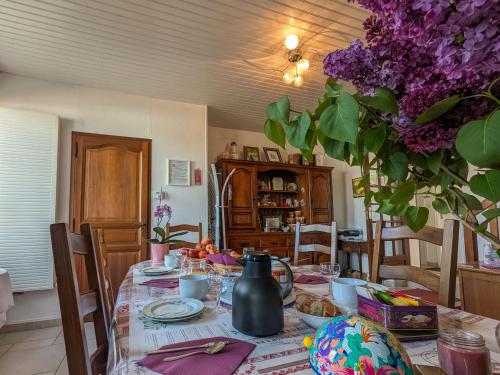 une table de salle à manger avec une bouilloire et des fleurs violettes dans l'établissement Chambres d'hôtes Berry: Nature et détente près des Châteaux de la Loire - FR-1-591-690, à Châtillon-sur-Indre