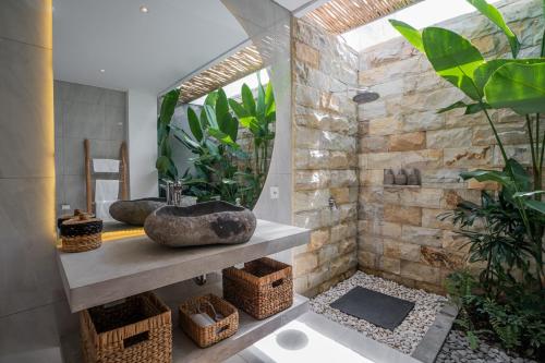 een badkamer met twee wastafels en een stenen muur bij NEW! Tropical Palms Villa - 4BR Villa in Kerobokan in Kerobokan