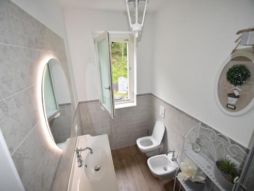 a bathroom with a sink and a toilet and a mirror at Apartment near Lake Maggiore in Meina