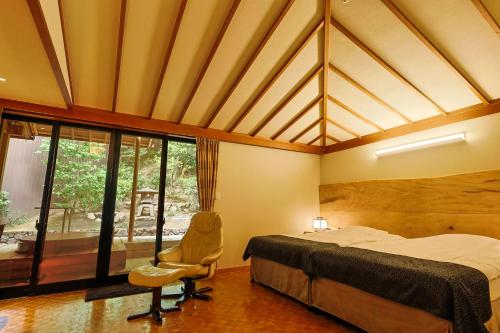 a bedroom with a bed and a chair and a window at Ginsuisou Choraku in Kobe
