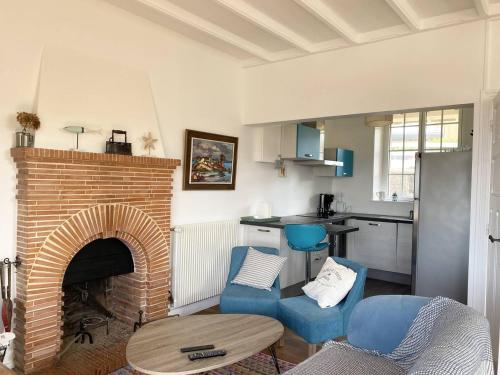 - un salon doté d'une cheminée en briques et de chaises bleues dans l'établissement Villa à Perros-Guirec avec vue mer, jardin, terrasse, 400m de la plage, WIFI - FR-1-368-42, à Perros-Guirec