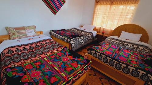 a room with three beds with colorful blankets at Munay Wasi in Puno