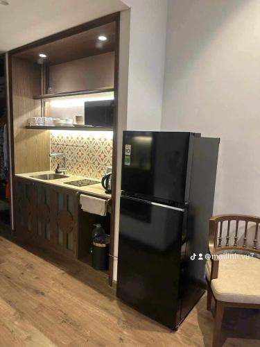 a kitchen with a black refrigerator and a sink at Apec Mandala Sea View Bathtub by MLT in Mui Ne