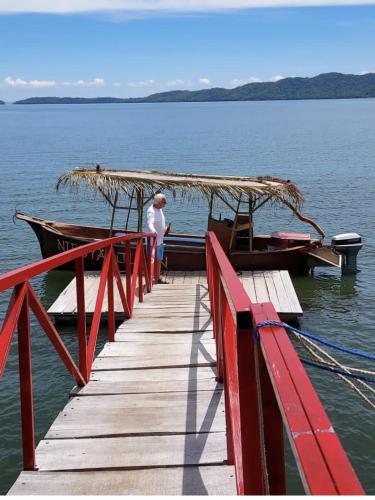 a man standing on a dock next to a boat at La Perla Negra Eco Pirate Resort in Puntarenas