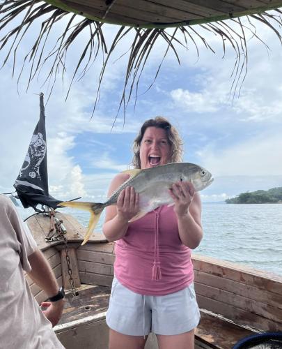 a woman holding a fish in a boat at La Perla Negra Eco Pirate Resort in Puntarenas