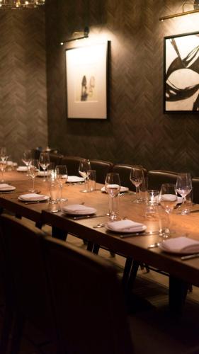 a long wooden table with wine glasses and napkins at Hotel Seville NoMad - The Unbound Collection by Hyatt in New York