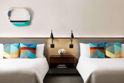 two beds with colorful pillows in a hotel room at Hotel Seville NoMad - The Unbound Collection by Hyatt in New York