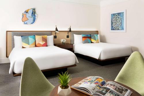 two beds in a room with a table and chairs at Hotel Seville NoMad - The Unbound Collection by Hyatt in New York