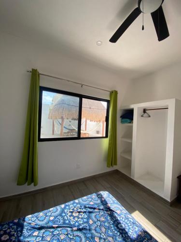 a bedroom with a ceiling fan and a window at Casa Loto B in Chelem