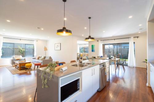 an open kitchen and living room with a couch at Lux Clyde North Super Spacious Retreat in Clyde North