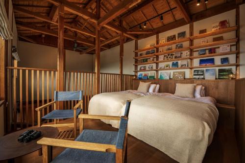 a bedroom with two beds and a chair in it at TheMana Village in Tosashimizu