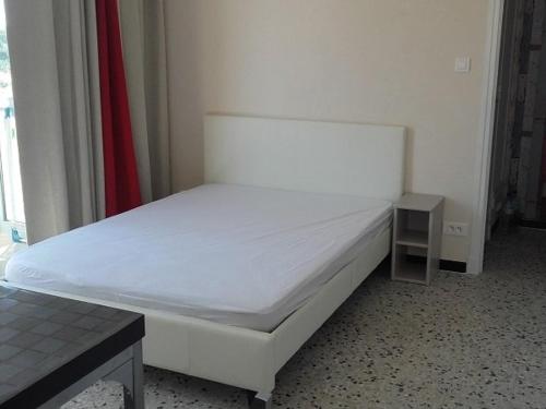- un lit blanc dans une chambre avec une petite table dans l'établissement Studio 2 Pers Proche Plage avec Parking Privé - FR-1-833-23, à Canet