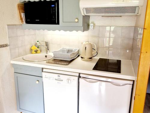 une petite cuisine avec un évier et un micro-ondes dans l'établissement Charmant studio cabine près des pistes à La Plagne Montalbert - FR-1-755-38, à Aime La Plagne