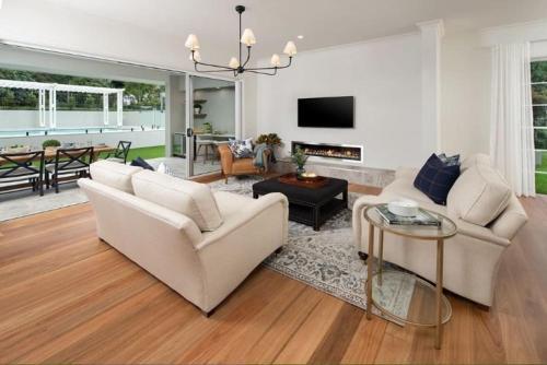 a living room with two white couches and a fireplace at Treehaven Estate - A Luxe Nature Escape with Pool in Maleny