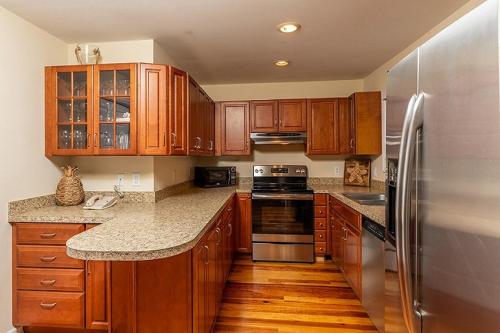 a kitchen with wooden cabinets and a stainless steel refrigerator at Sandpiper Court 14 by Wild Dunes, with Amenities in Isle of Palms