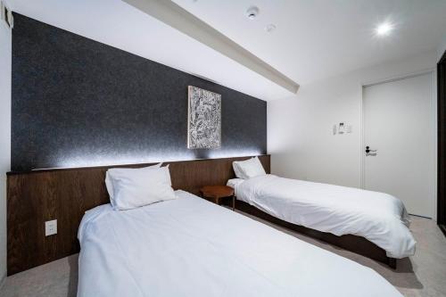 two beds in a hotel room with white sheets at Taketo Stay Kotoni 302 in Sapporo