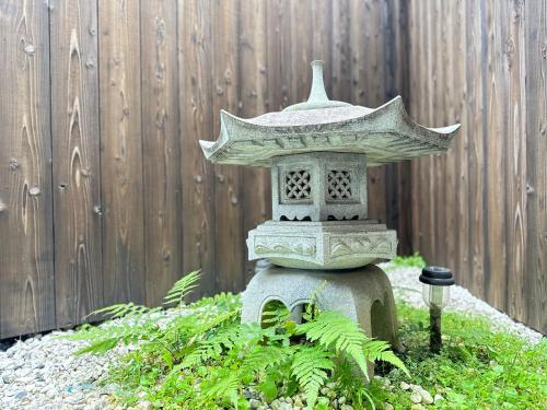 um pagode de pedra em um jardim em frente a uma cerca em nestay東九条01左側 em Quioto