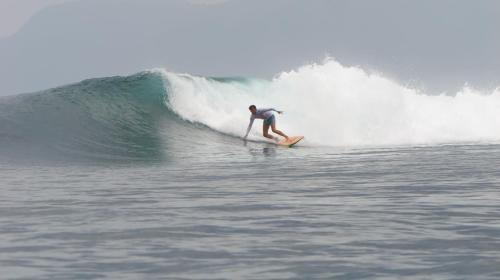 a man riding a wave on a surfboard in the ocean at White Guest House in Sekongkang