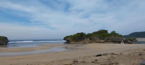 a sandy beach with rocks and the ocean at White Guest House in Sekongkang
