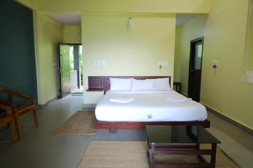 a bedroom with a white bed in a room at Hong Sau Resort in Sakleshpur