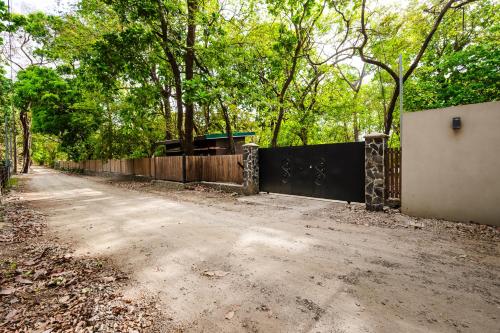 a fence next to a dirt road with trees at 2 Nature Villas with Pool in Santa Cruz