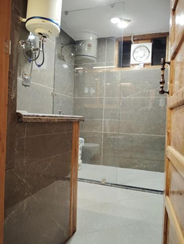 a bathroom with a shower with a glass door at Hotel CM Palace - Pure Vegetarian in Ner Chowk