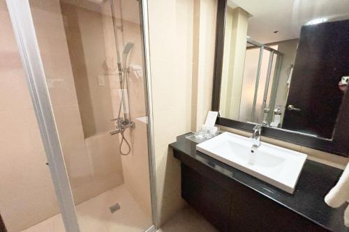 a bathroom with a sink and a shower with a mirror at The Muse Hotel Boracay in Boracay