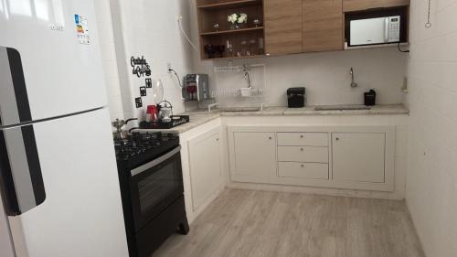 a kitchen with white cabinets and a black stove at Apartamento inteiro 2 quartos Porto Barra Vista Mar in Salvador