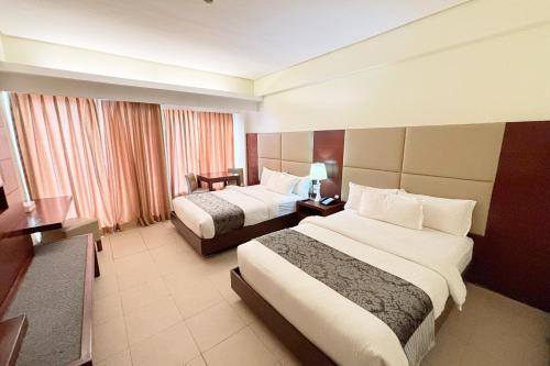 a hotel room with two beds and a television at The Muse Hotel Boracay in Boracay