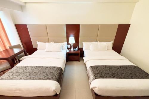 a hotel room with two beds and a table at The Muse Hotel Boracay in Boracay