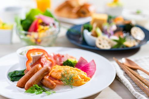 a plate of food with sausage and vegetables on a table at Ooedo Onsen Monogatari Unazuki Grand Hotel in Kurobe