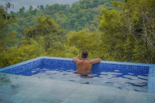 un homme dans une piscine avec vue dans l'établissement Yakurungala Nature Resort Kandy, à Kandy