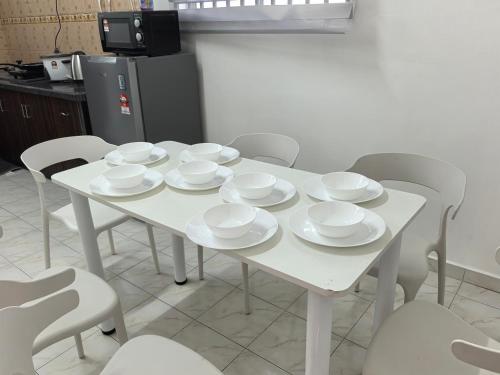 a white table with white cups and saucers on it at Padang Serai Harmoni Homestay in Padang Serai