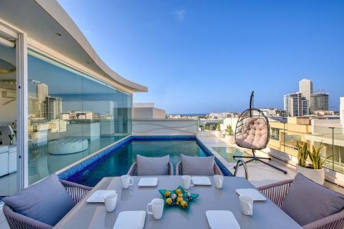 a balcony with a table and a swimming pool at Luxury Penthouse in Swieqi with In and Outdoor Pool in Tal-Għoqod