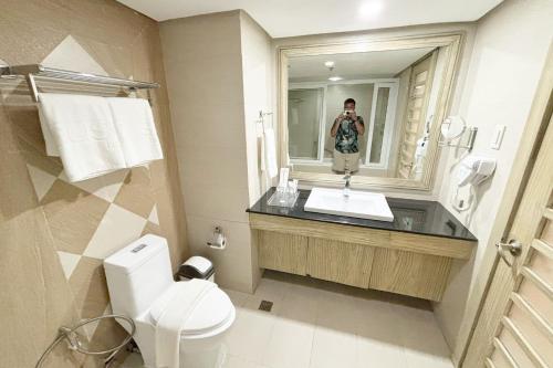 a man taking a picture of a bathroom mirror at The Muse Hotel Boracay in Boracay
