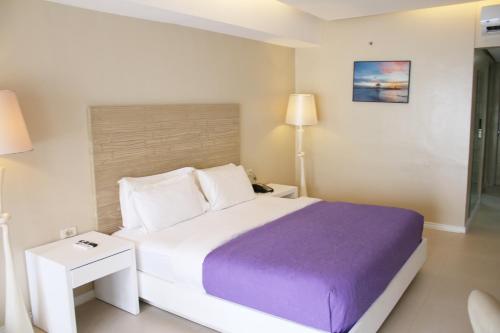 a bedroom with a large bed with a purple blanket at The Muse Hotel Boracay in Boracay